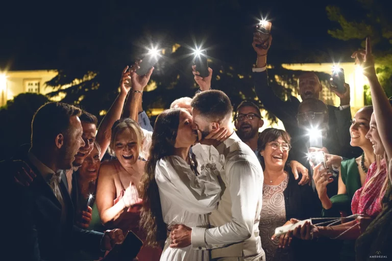 signature photo de Amédézal, les mariés s'embrassent entourés de leurs amis et famille à la Bastide d'Astres
