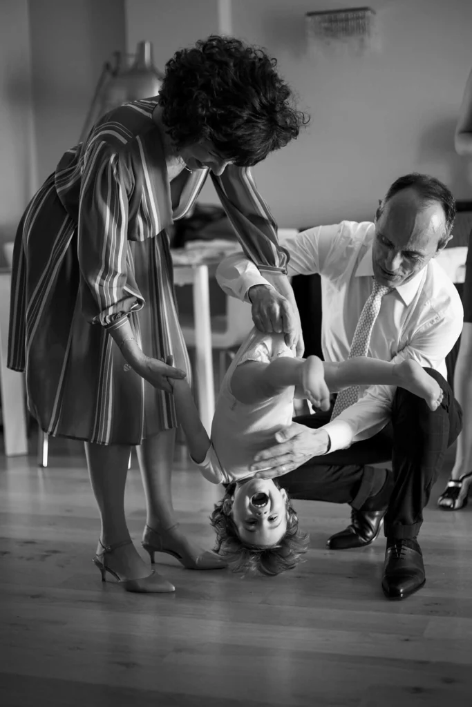 Grands-parents faisant tournoyer leur petit-enfant à l'envers et riant, portrait noir et blanc, séance photo famille Amedezal dans la Loire
