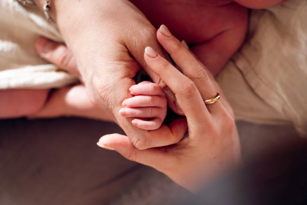 Minuscule main de nouveau-né agrippant le doigt d'un parent, détail photographié lors d'une séance naissance par Amedezal dans la Loire